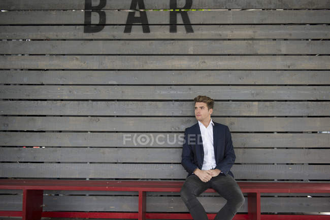 Mann sitzt auf Bank hinter Bar — Stockfoto