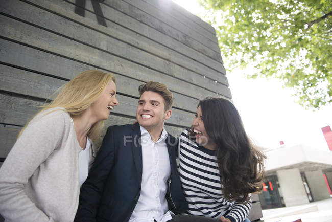 Friends sitting on bench and having fun — Stock Photo