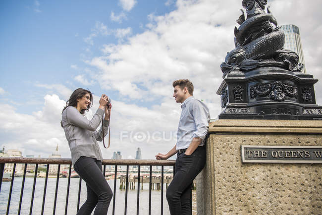 Woman taking photographs of young man — Stock Photo