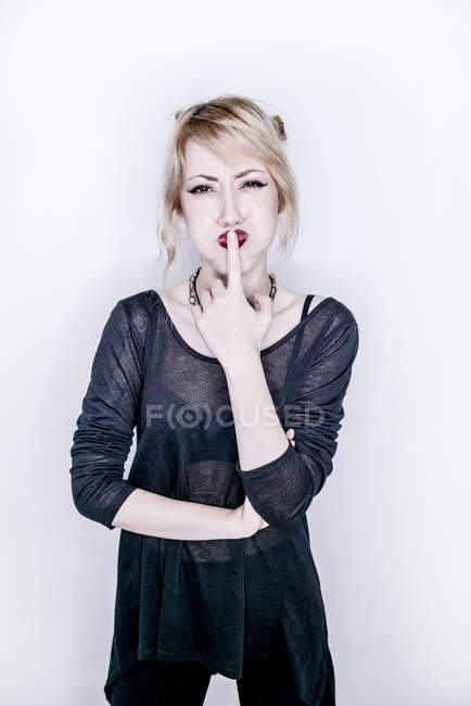 Woman looking sceptical with finger on lips — Stock Photo
