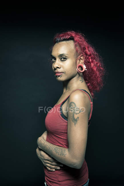 Retrato de mujer con brazos y piercings tatuados - foto de stock