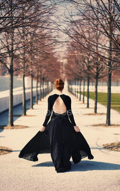 Donna che cammina lungo viale di alberi — Foto stock