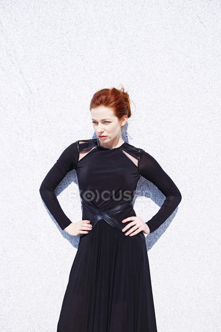Женщина в черном платье против мраморной стены — стоковое фото