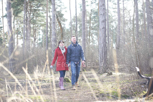 Caminhada de casal com cão em floresta — Fotografia de Stock