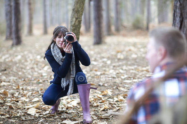 Mulher tira foto de parceiro na floresta — Fotografia de Stock