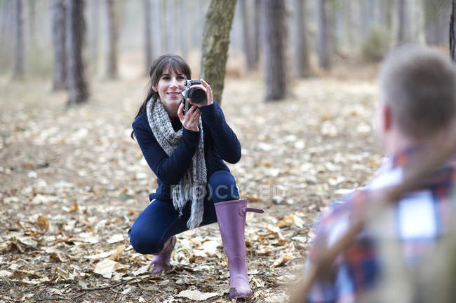 Mujer toma la foto de la pareja en el bosque - foto de stock
