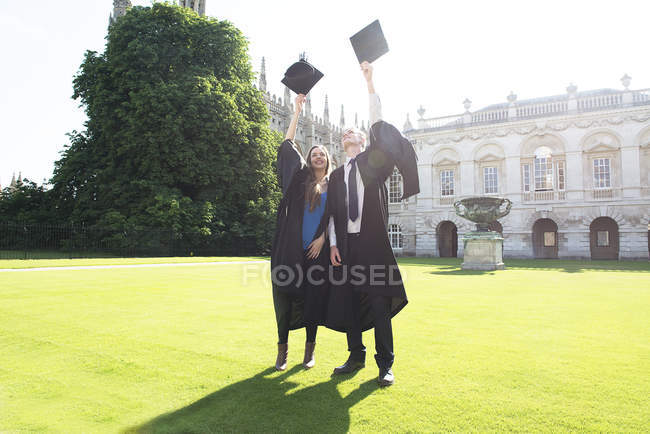 Étudiants en robes de remise des diplômes jetant des panneaux de mortier — Photo de stock