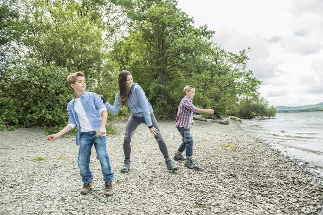 Женщина и двое мальчиков играли на берегу — стоковое фото