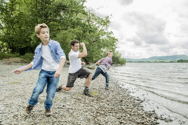 Homem e dois meninos skimming pedras — Fotografia de Stock
