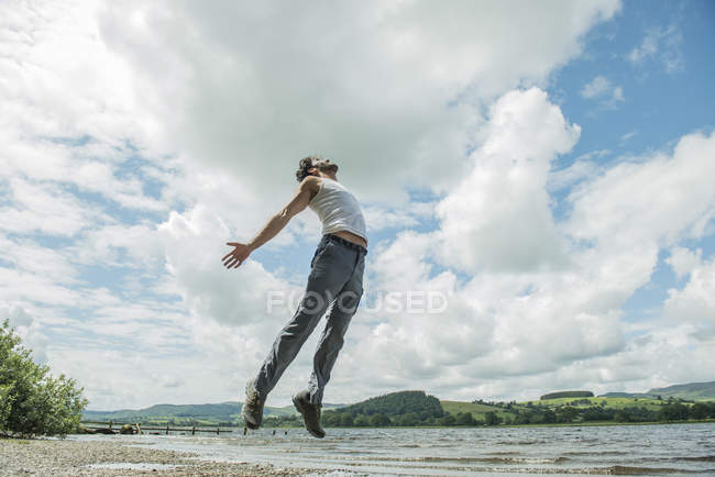 Людина стрибає в повітря на березі — стокове фото