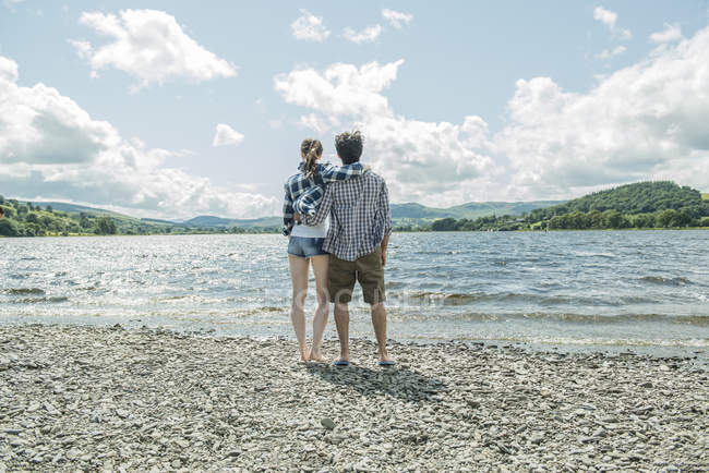 Man and woman standing holding hands on shore — Stock Photo