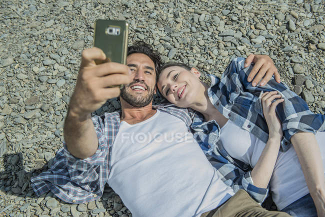 Hombre y mujer tomando selfie en la orilla - foto de stock