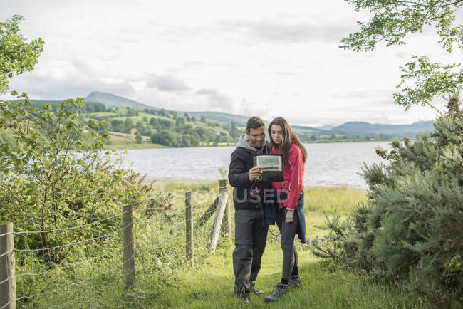 Man and woman looking at map on shore — Stock Photo