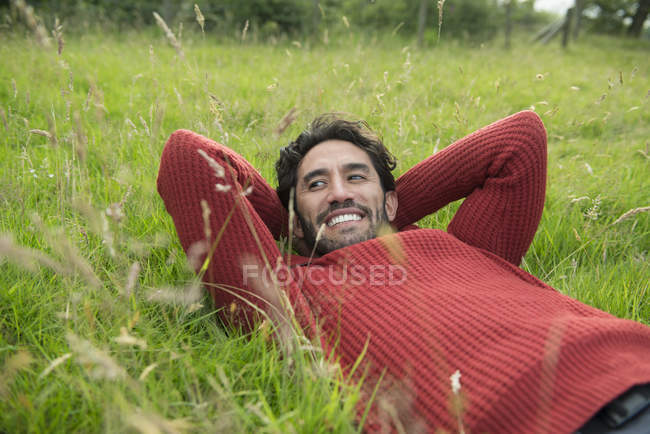 Hombre en puente rojo relajándose en la hierba - foto de stock