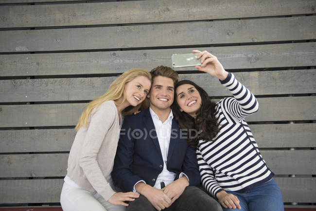 Amigos sentados en el banco tomando selfie - foto de stock
