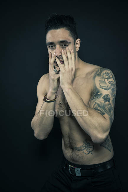 Tattooed man covering face with hands — Stock Photo