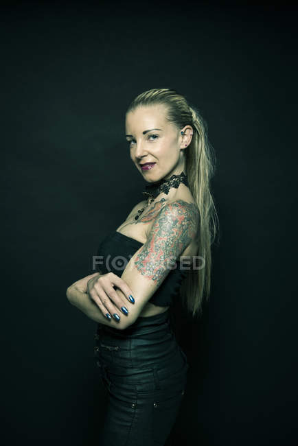 Femme debout avec les bras croisés tatoués — Photo de stock