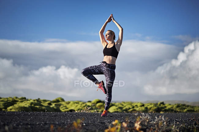 Женщина практикует йогу по безлюдной дороге — стоковое фото