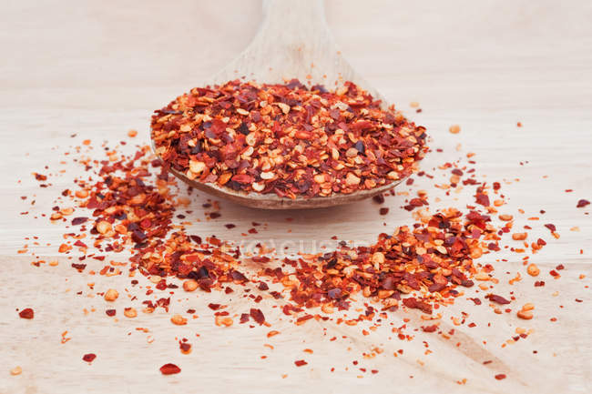 Crushed chillies on wooden serving spoon — Stock Photo