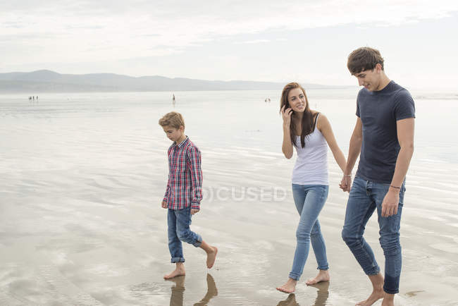 Paar und Sohn spazieren bei Sonnenschein am Strand — Stockfoto
