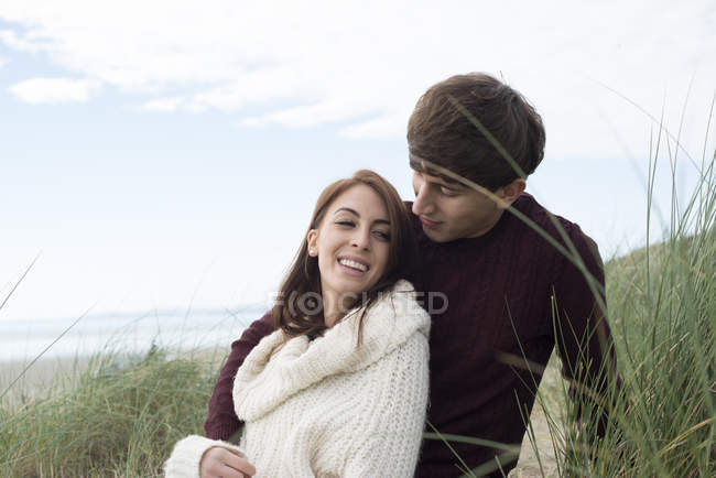 Casal abraçando em dunas na praia — Fotografia de Stock