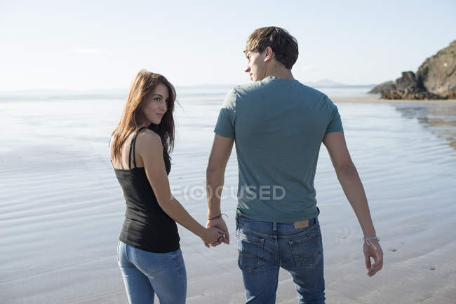 Paar läuft Händchenhaltend über Strand — Stockfoto