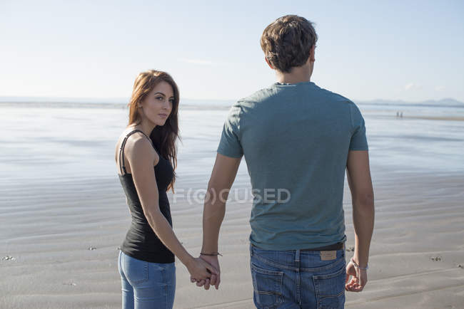 Пара прогулянка тримає руки через пляж — стокове фото