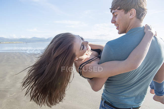 Homem transportando parceiro em toda a praia — Fotografia de Stock