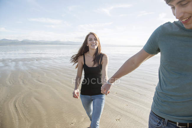Pareja caminar cogido de la mano a través de playa - foto de stock