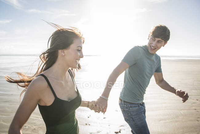 Casal correndo enquanto de mãos dadas na praia — Fotografia de Stock