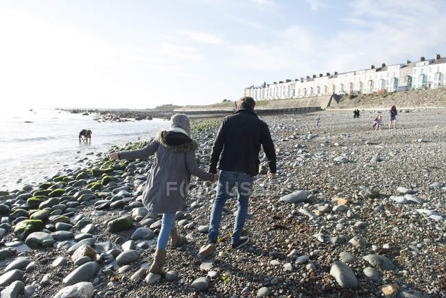 Casal andando enquanto segurando as mãos na praia — Fotografia de Stock