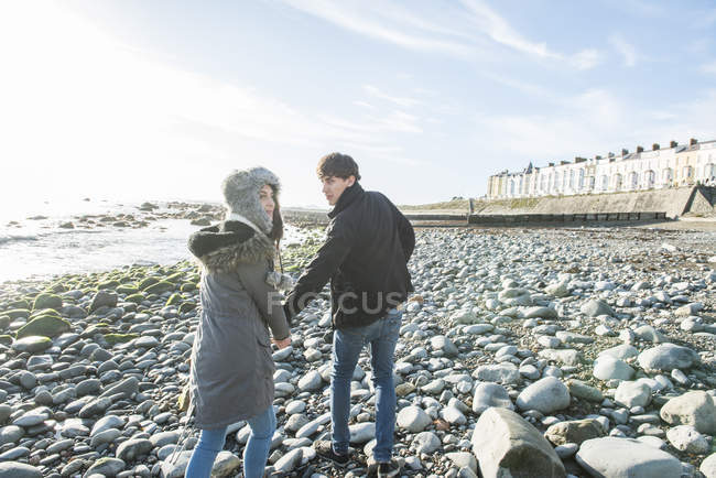 Пара ходьба в то время как держась за руки на пляже — стоковое фото