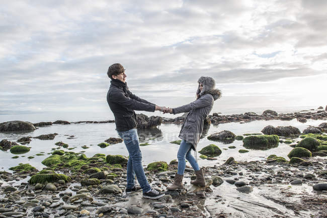 Couple walking whilst holding hands on beach — Stock Photo