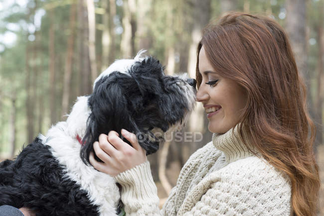 Жінка погладжує собаку на лісовій прогулянці — стокове фото
