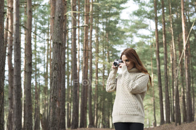 Mulher usando câmera vintage na floresta — Fotografia de Stock