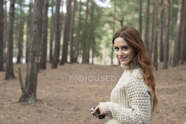 Donna utilizzando fotocamera vintage nella foresta — Foto stock