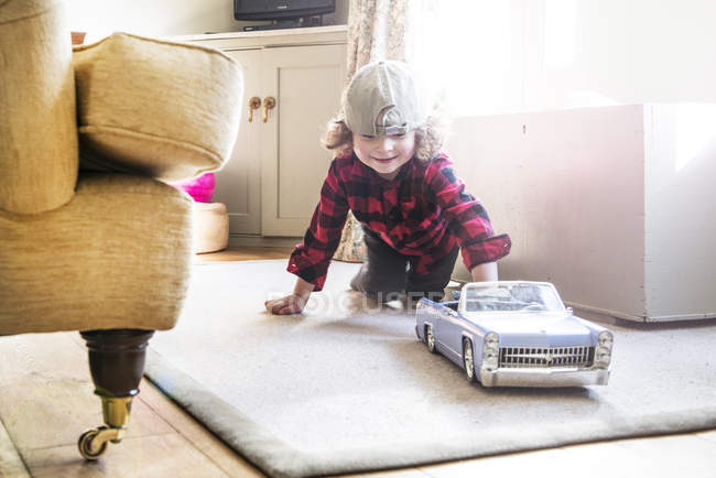 Boy in baseball cap playing with toy car — Stock Photo