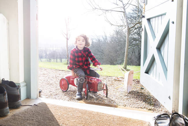Хлопчик сидить на іграшковому тракторі — стокове фото