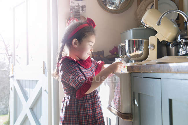 Chica lavando platos en fregadero de cocina - foto de stock