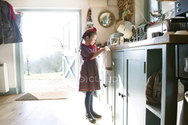 Girl washing dishes at kitchen sink — Stock Photo