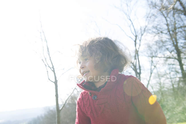 Niño en puente rojo de pie en el jardín - foto de stock
