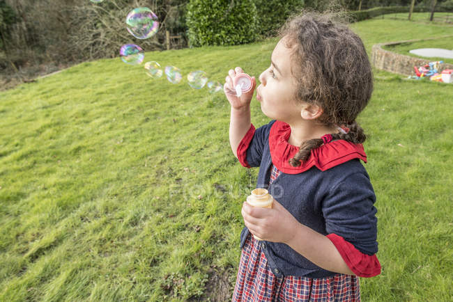 Дівчина дме бульбашки в саду — стокове фото