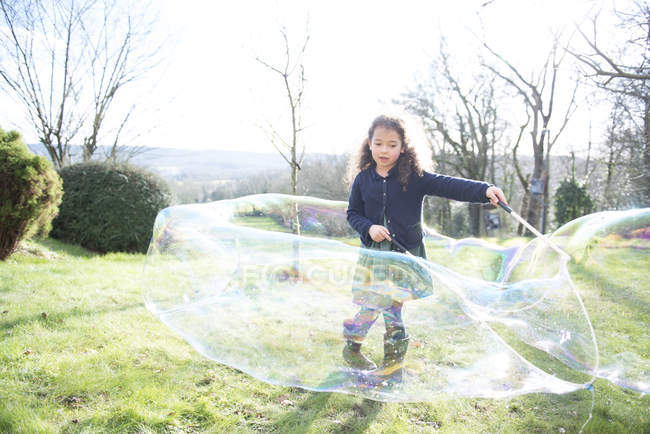 Mädchen erzeugt riesige Blasen im Garten — Stockfoto
