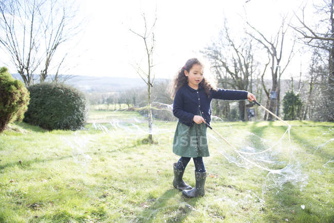 Дівчина створює величезні бульбашки в саду — стокове фото