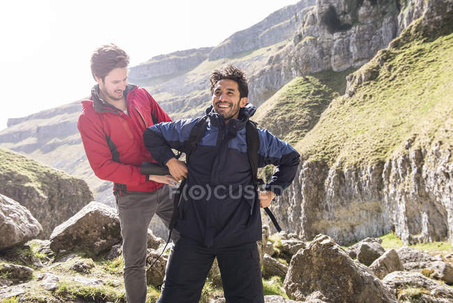 Montañista ayudando amigo con mochila - foto de stock