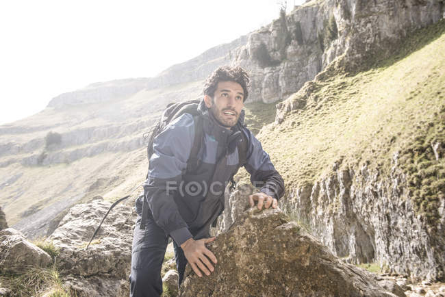Montanhista escalando sobre rochas em terreno acidentado — Fotografia de Stock