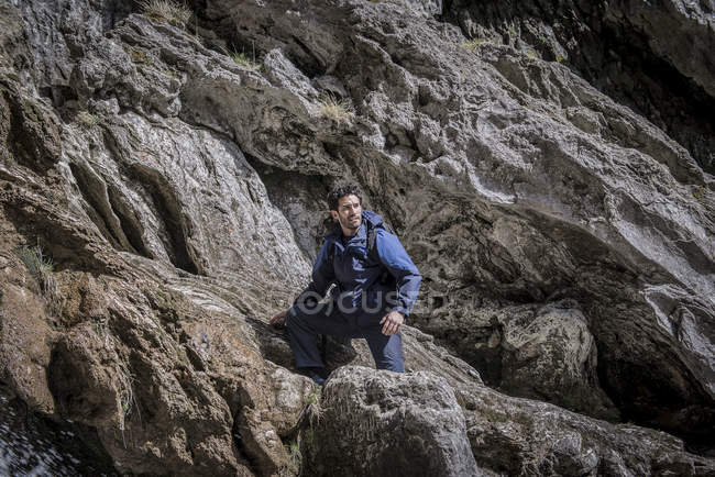 Alpiniste assis sur des rochers en terrain accidenté — Photo de stock