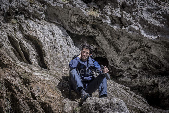 Montanhista sentado sobre rochas em terreno acidentado — Fotografia de Stock