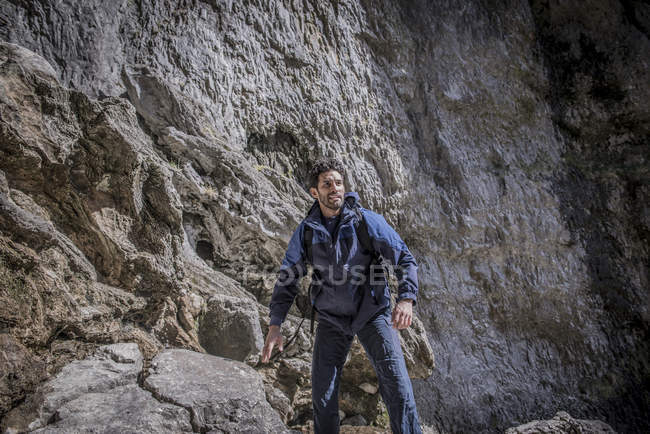 Bergsteiger steht in unwegsamem Gelände über Felsen — Stockfoto