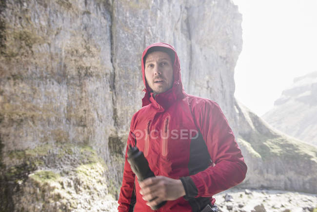 Bergsteiger steht mit Wasserflasche — Stockfoto